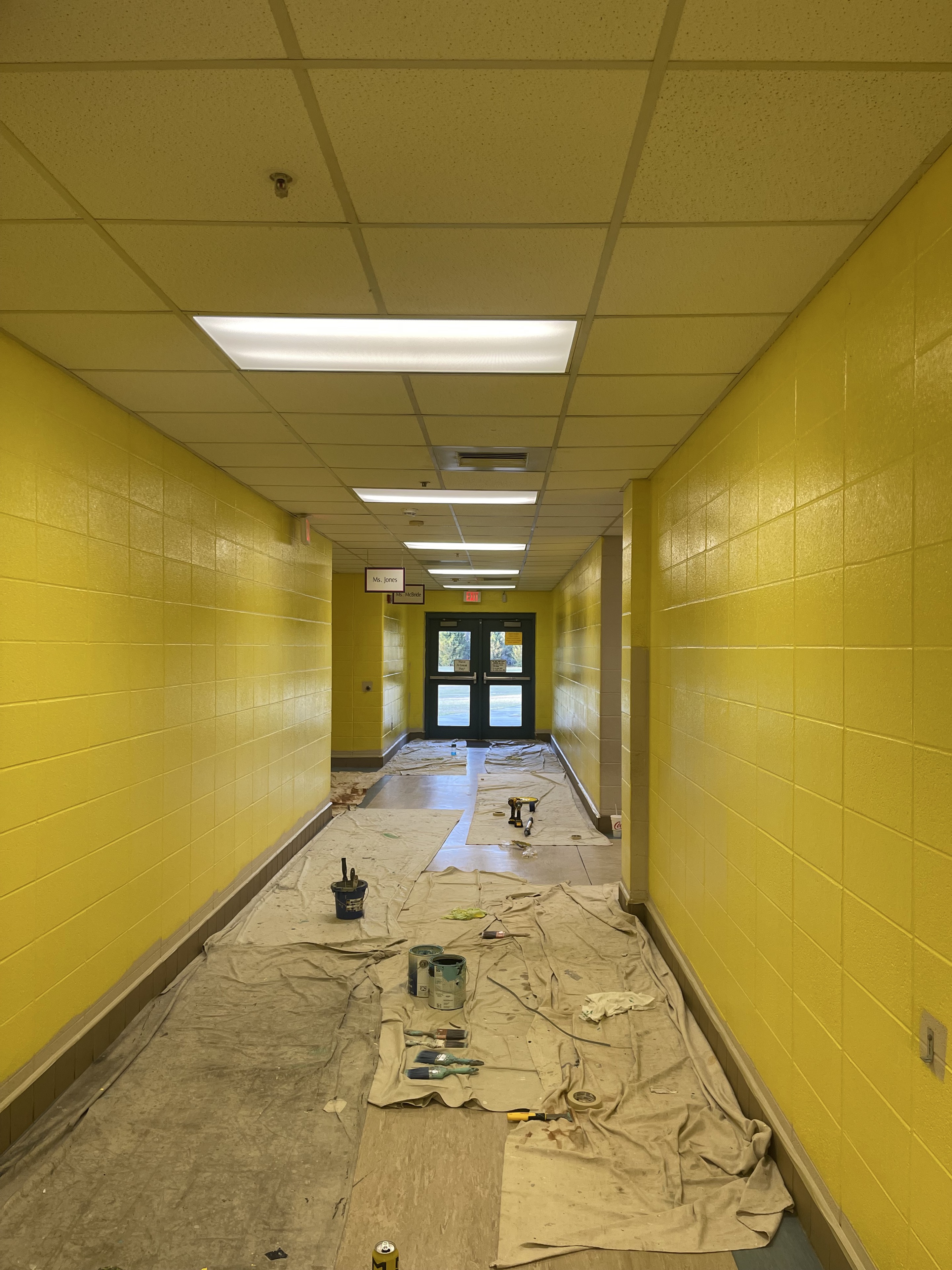 School corridor protected with drop cloths during a yellow repaint