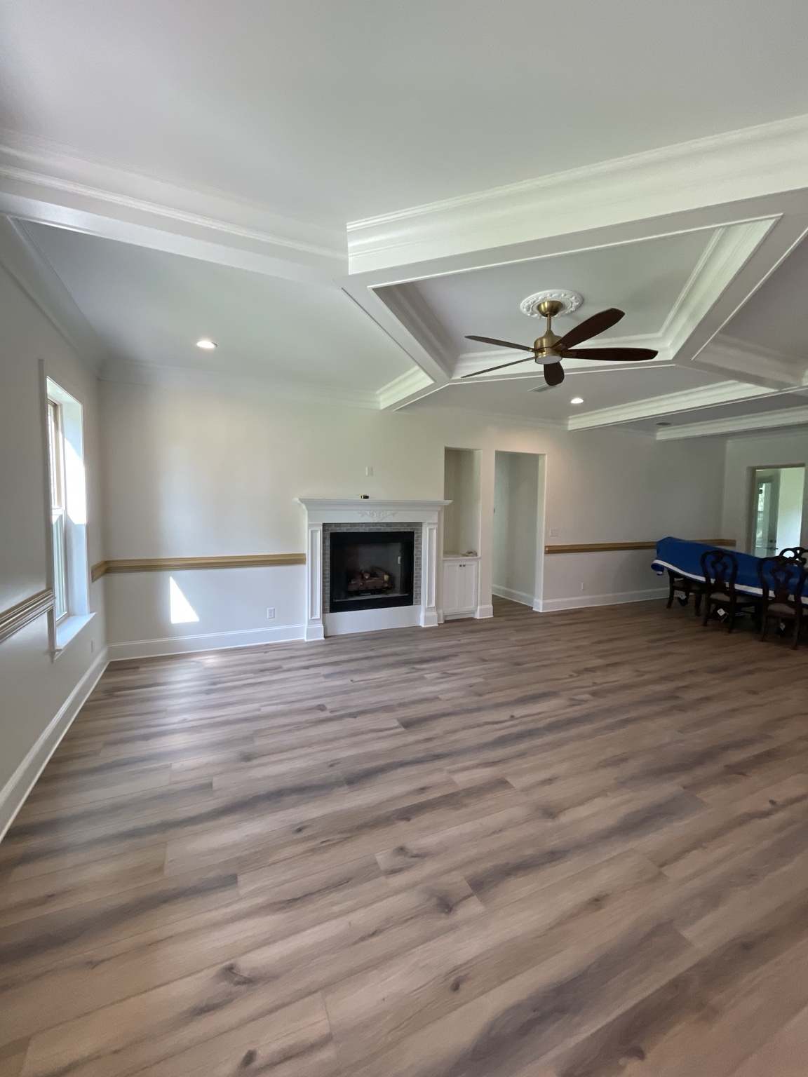 Finished new-construction living room with detailed ceiling, fireplace mantel, trim, and custom gold chair railing