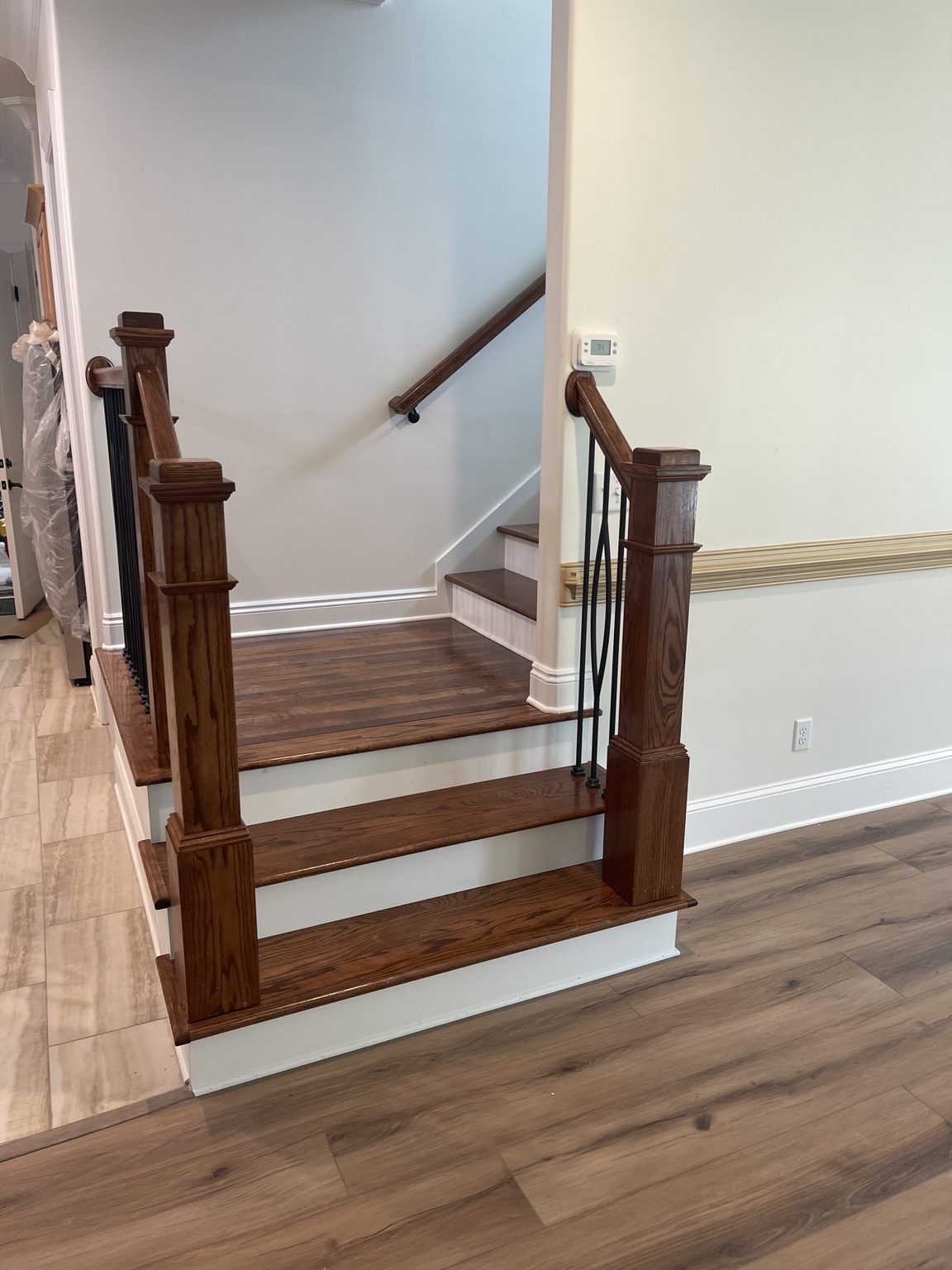 Finished new-construction stair landing with stained newel posts, treads, and handrails
